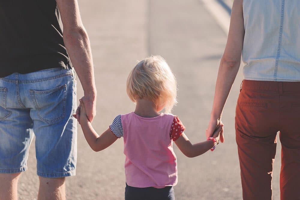 Little girl holding hands with parents