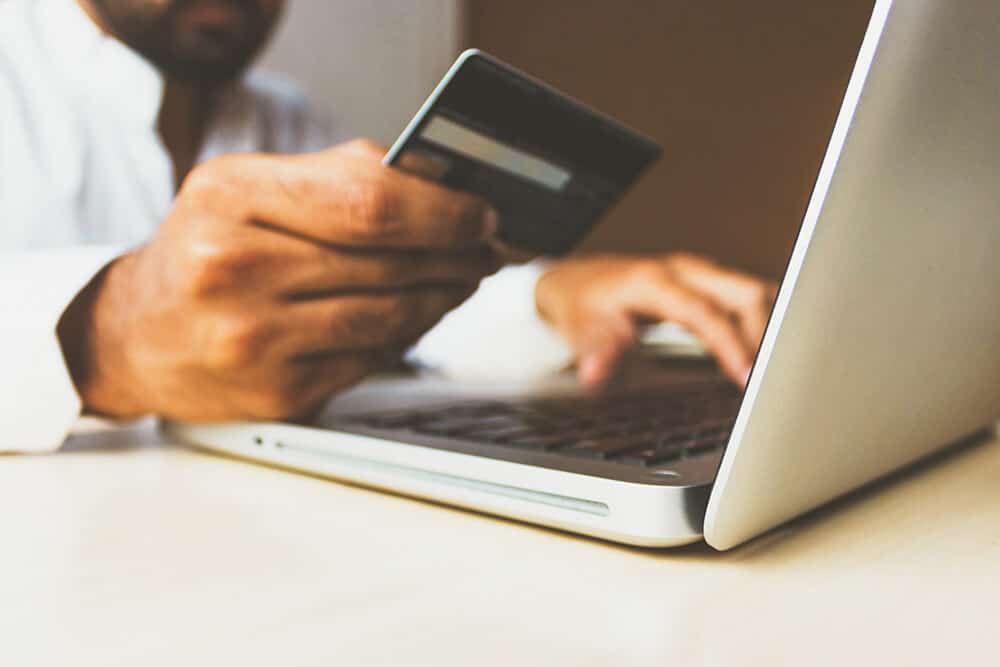 Person holding credit card while they're on their laptop