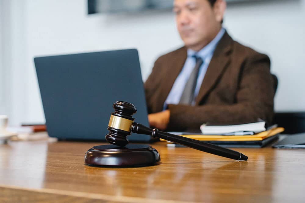 Person working on laptop with gavel on desk